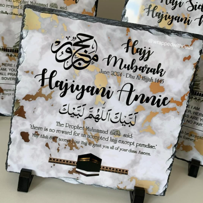 Personalized black slate plaque with Hajj and Iftar messages, displayed on a small stand in front of matching plaques.
