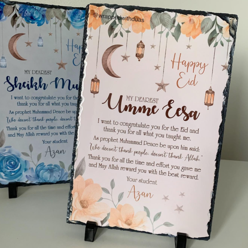 Personalized Islamic slate sign for Eid Mubarak featuring watercolor illustrations of crescent moons, lanterns, stars, and flowers, with custom text printed on a black slate board displayed on a small stand.